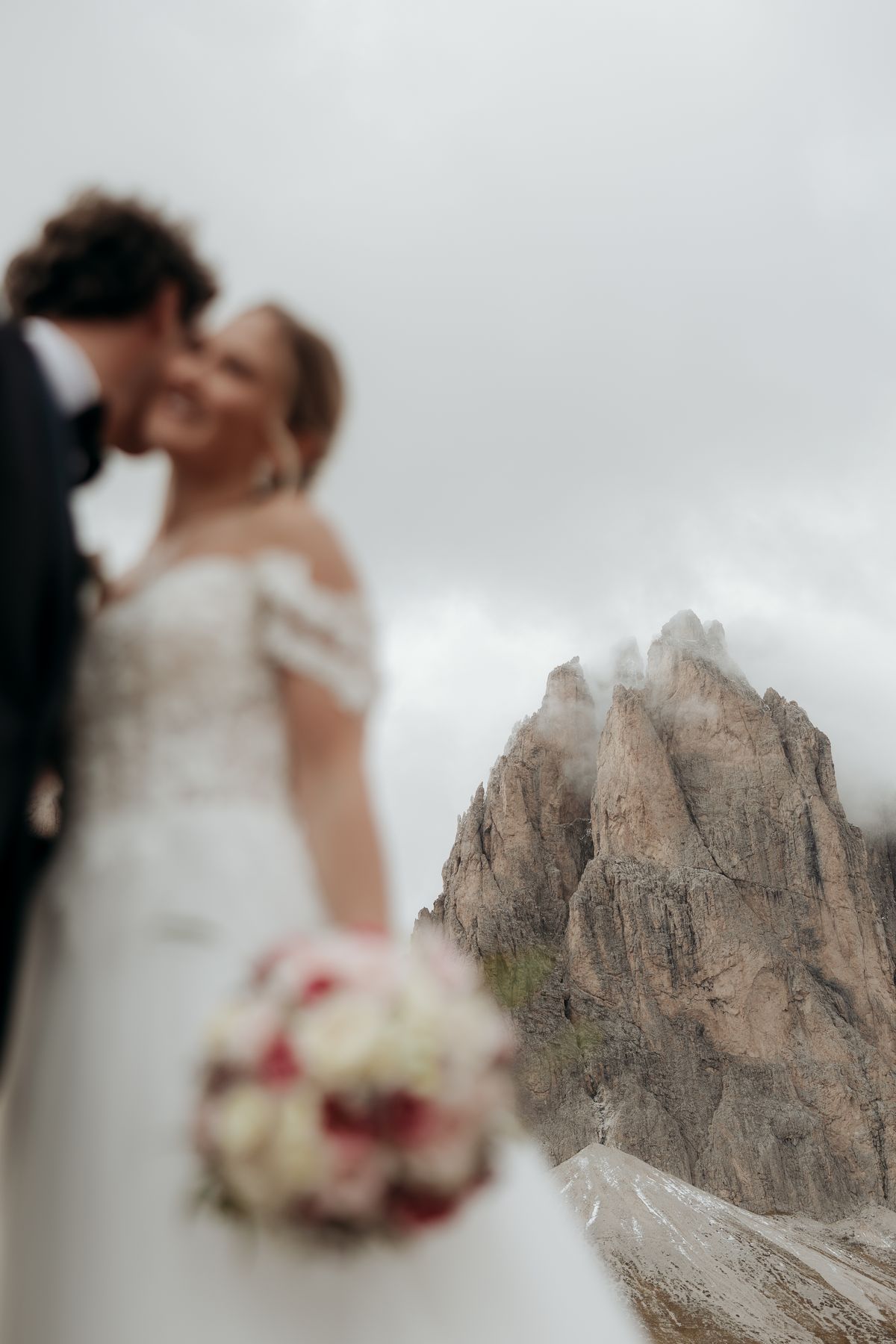 Kiss in front of a rock tower, the bride holding her bouquet