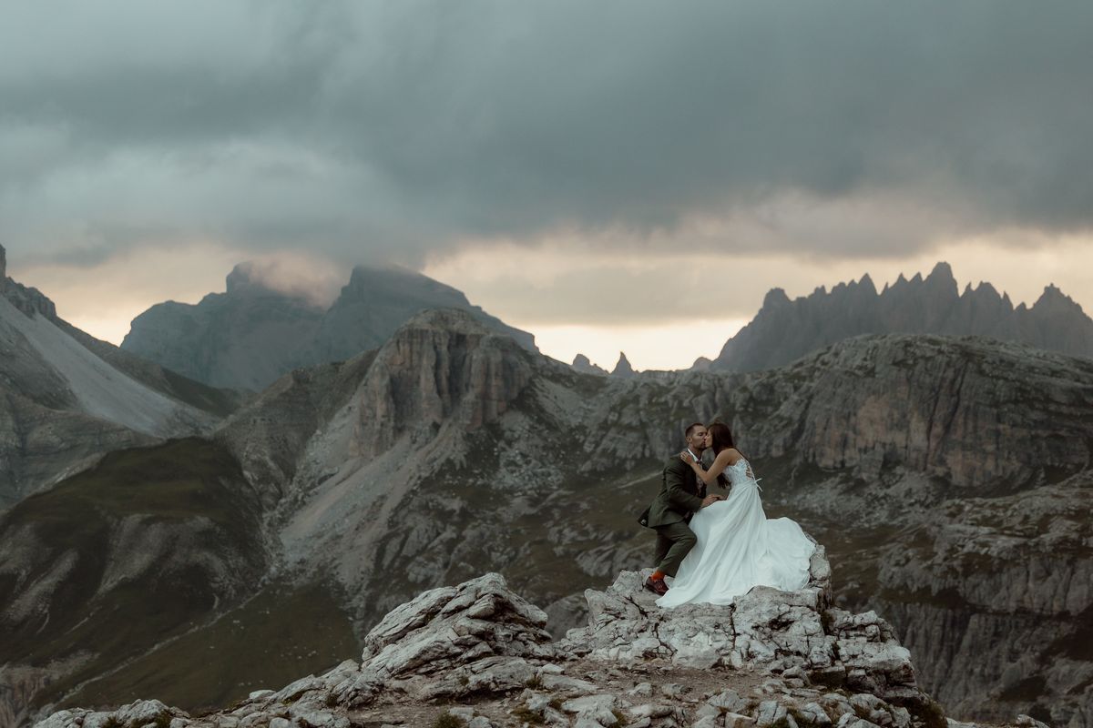 Couple on a rock near the Three Peaks under clouds