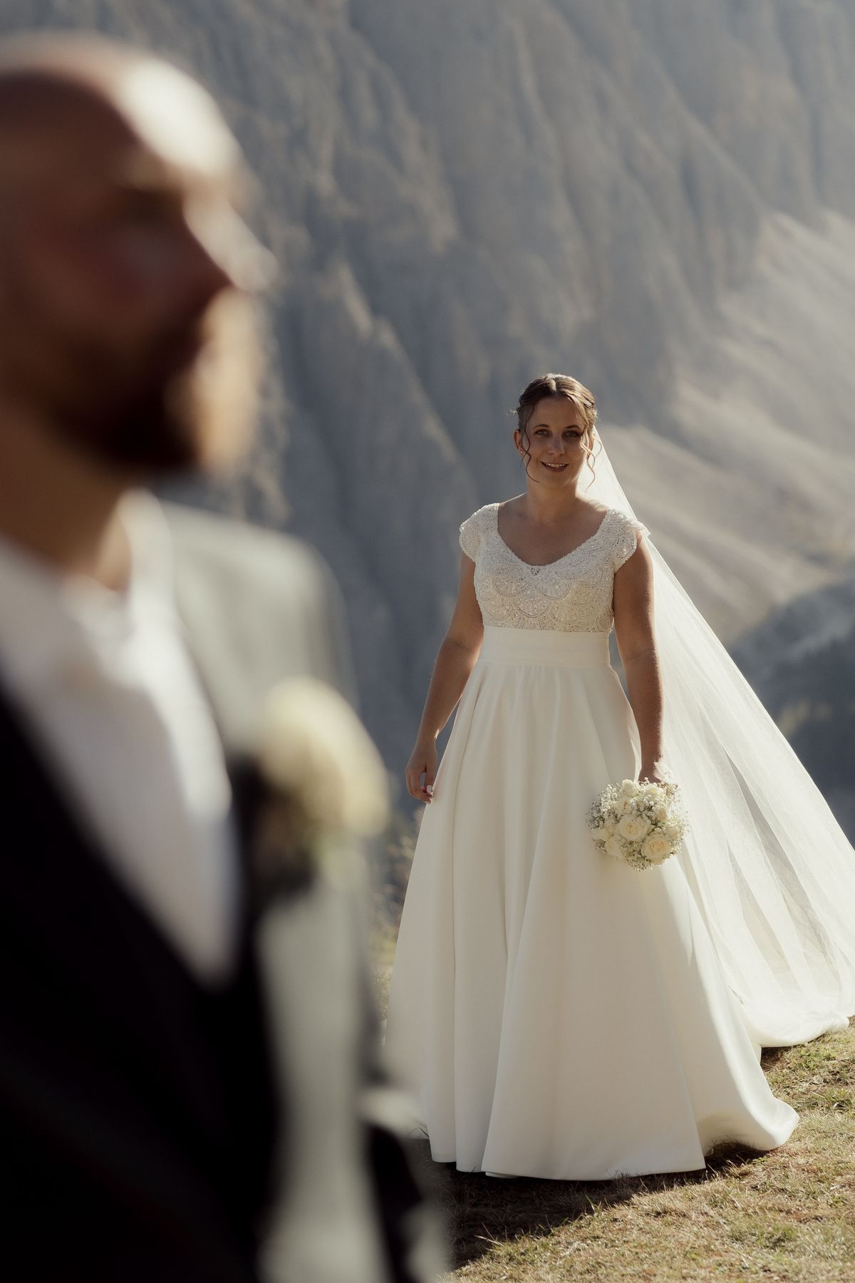 Bride with a veil on the meadow, the groom in the foreground