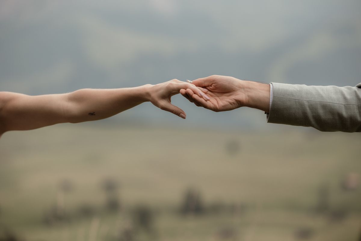Hands touching above an alpine meadow