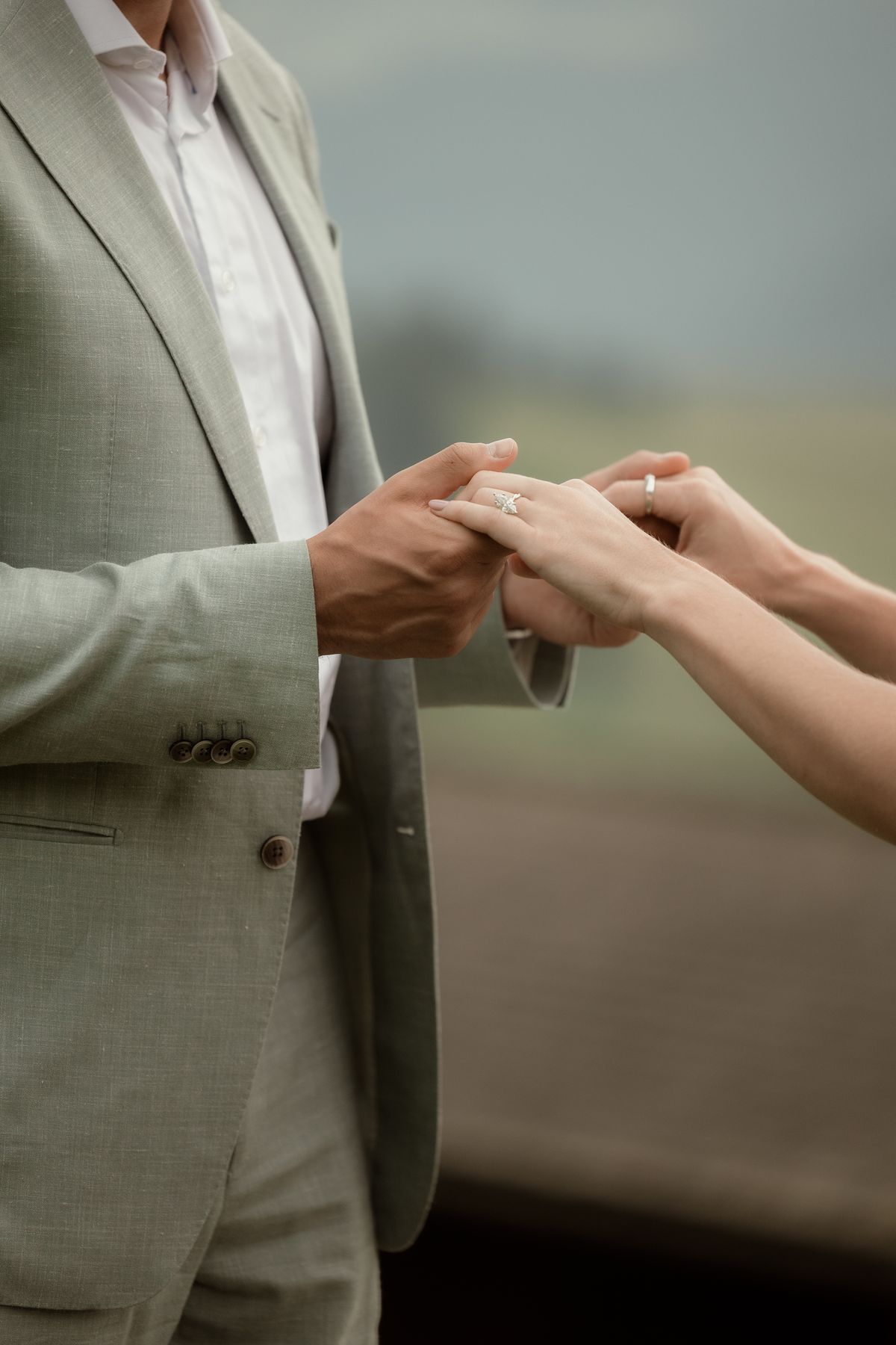 Groom holding the bride’s hand with the ring