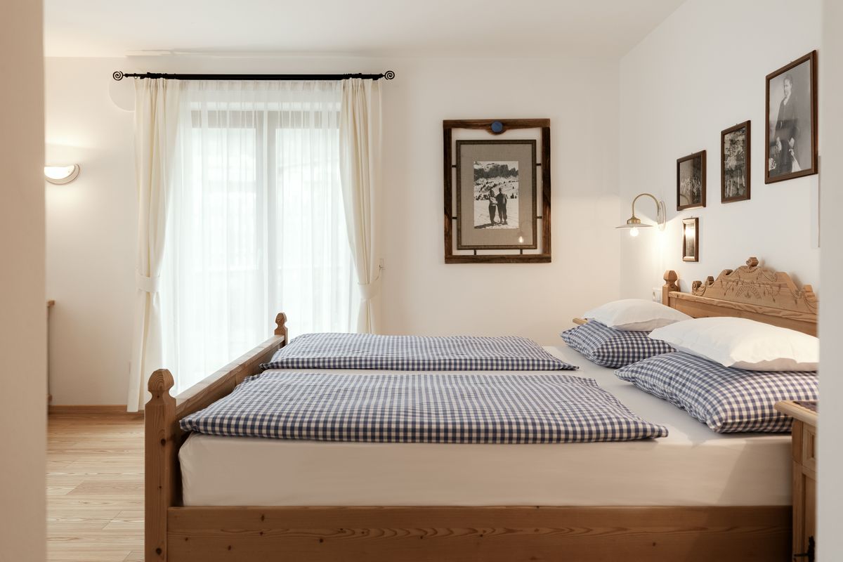 Schlafzimmer mit Holzbett und alten Fotografien