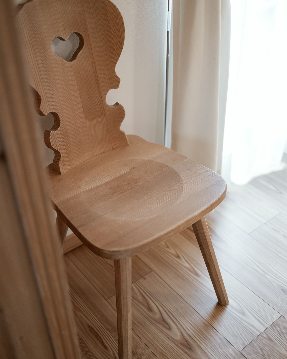 Wooden chair with a heart cut-out by the window