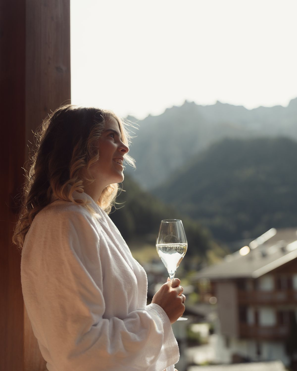 Guest in a bathrobe with a glass of sparkling wine on the balcony