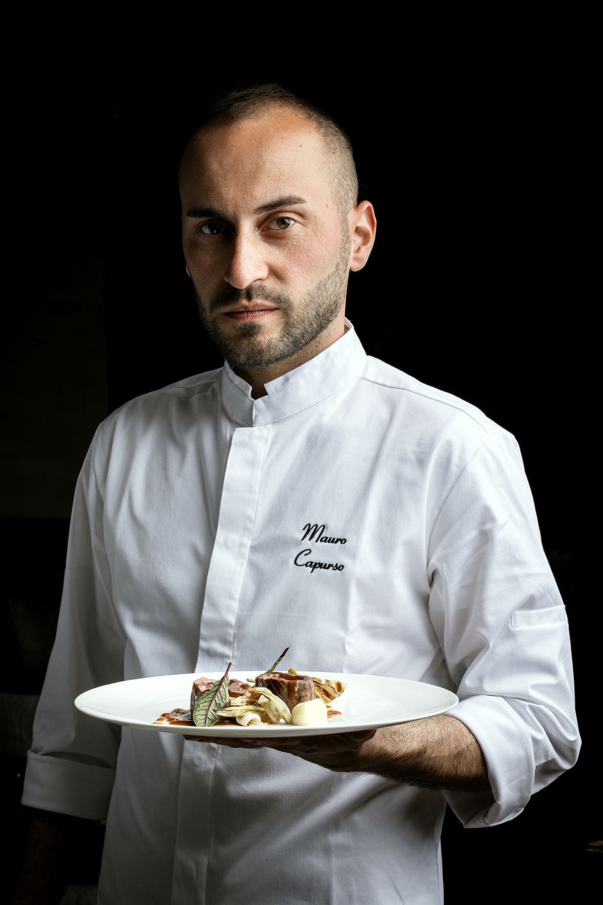 Chef with a plate against a dark background