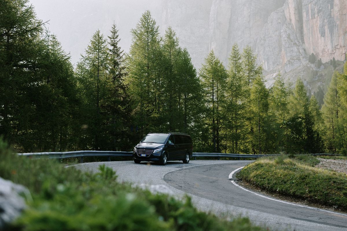Van rounding a bend below rock faces