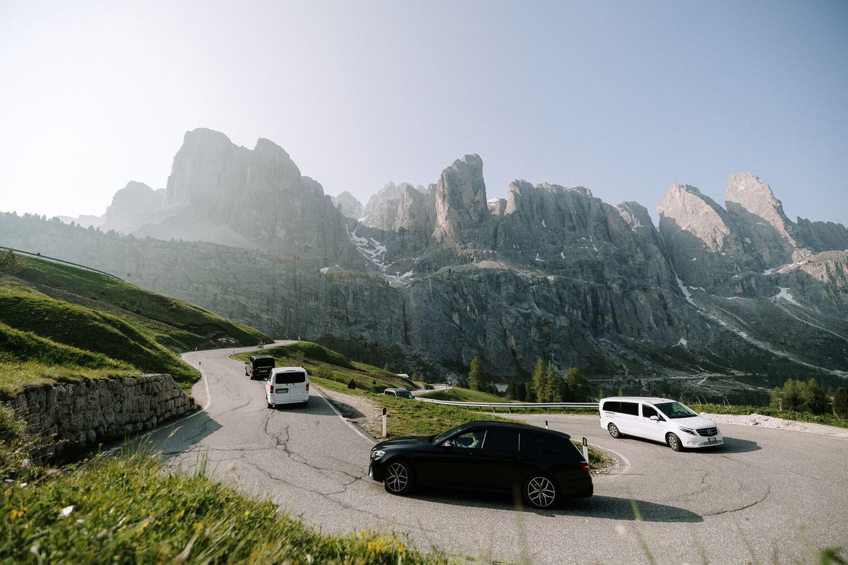 Vehicles on a hairpin below rocky peaks