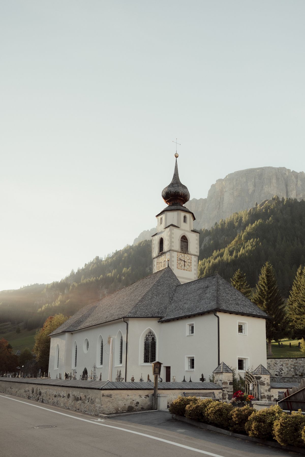White village church with an onion dome in front of the mountains