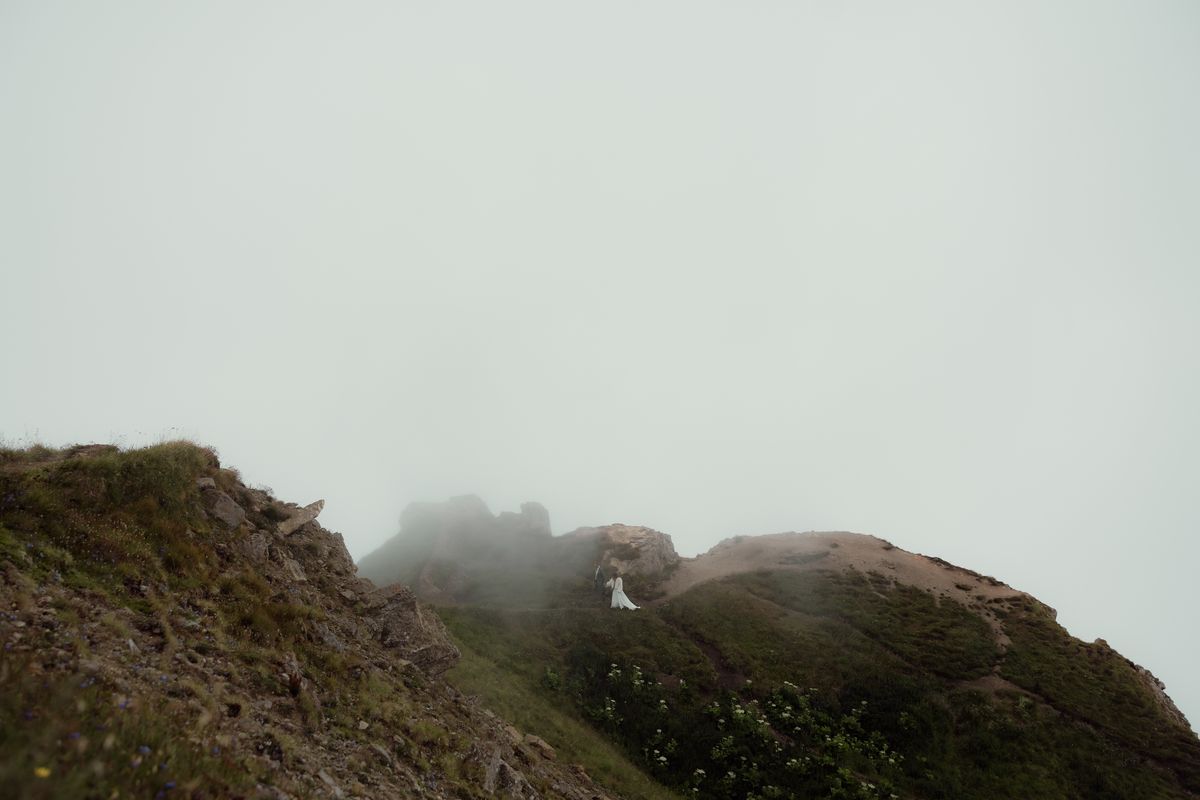 The couple, small, on a ridge in the fog