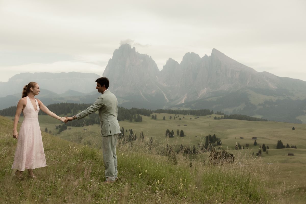 Paar Hand in Hand auf der Seiser Alm vor Langkofel und Plattkofel
