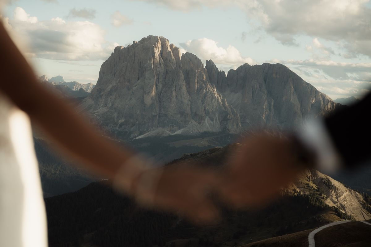 Couple holding hands with Sassolungo behind them