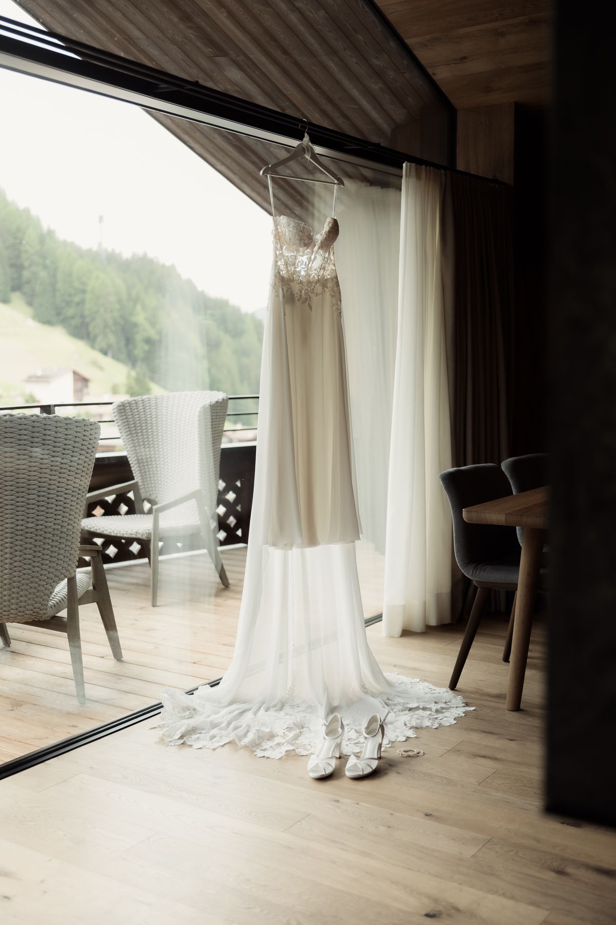 Wedding dress hanging by the window of a hotel room with mountain view