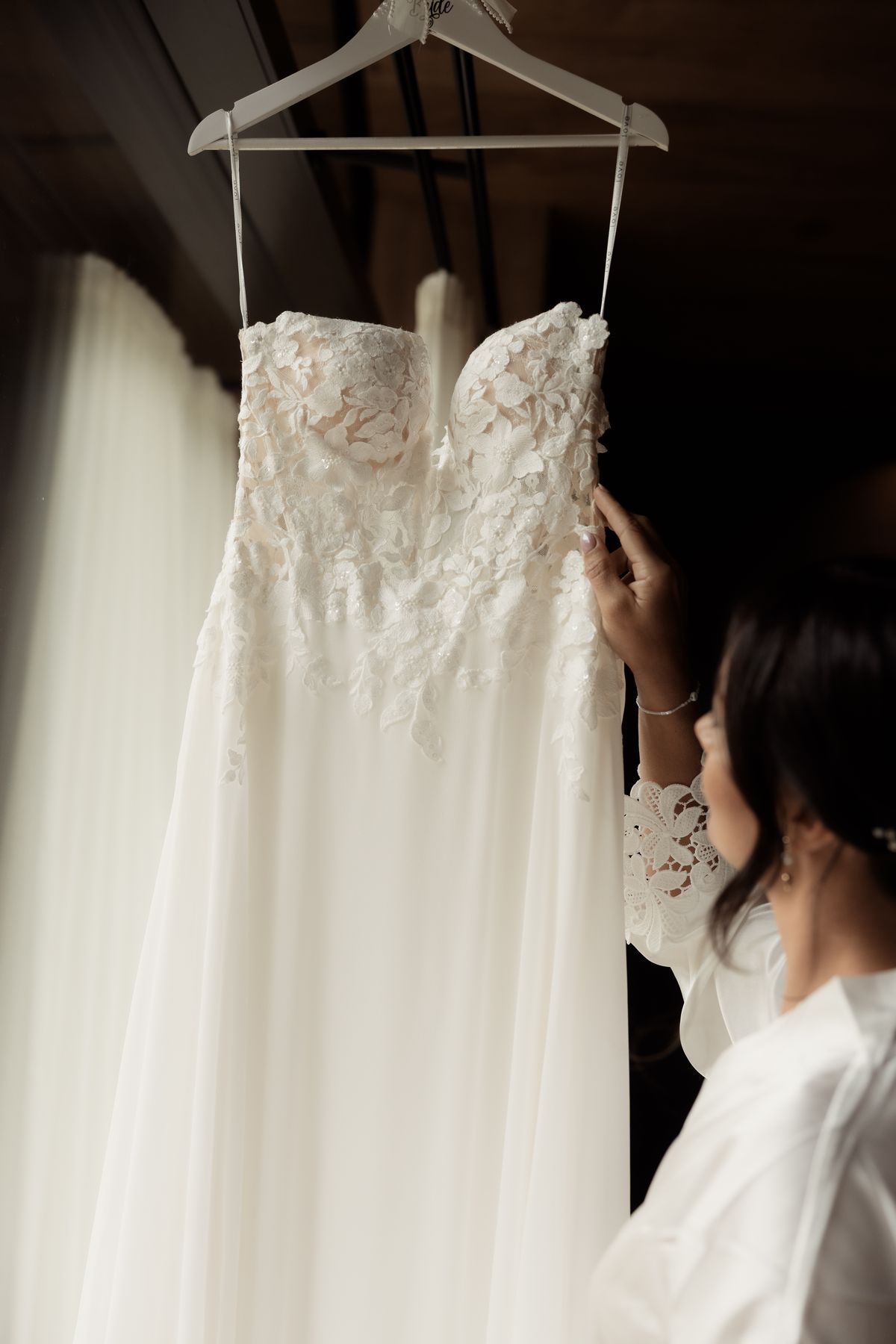Bride reaching for her dress on the hanger