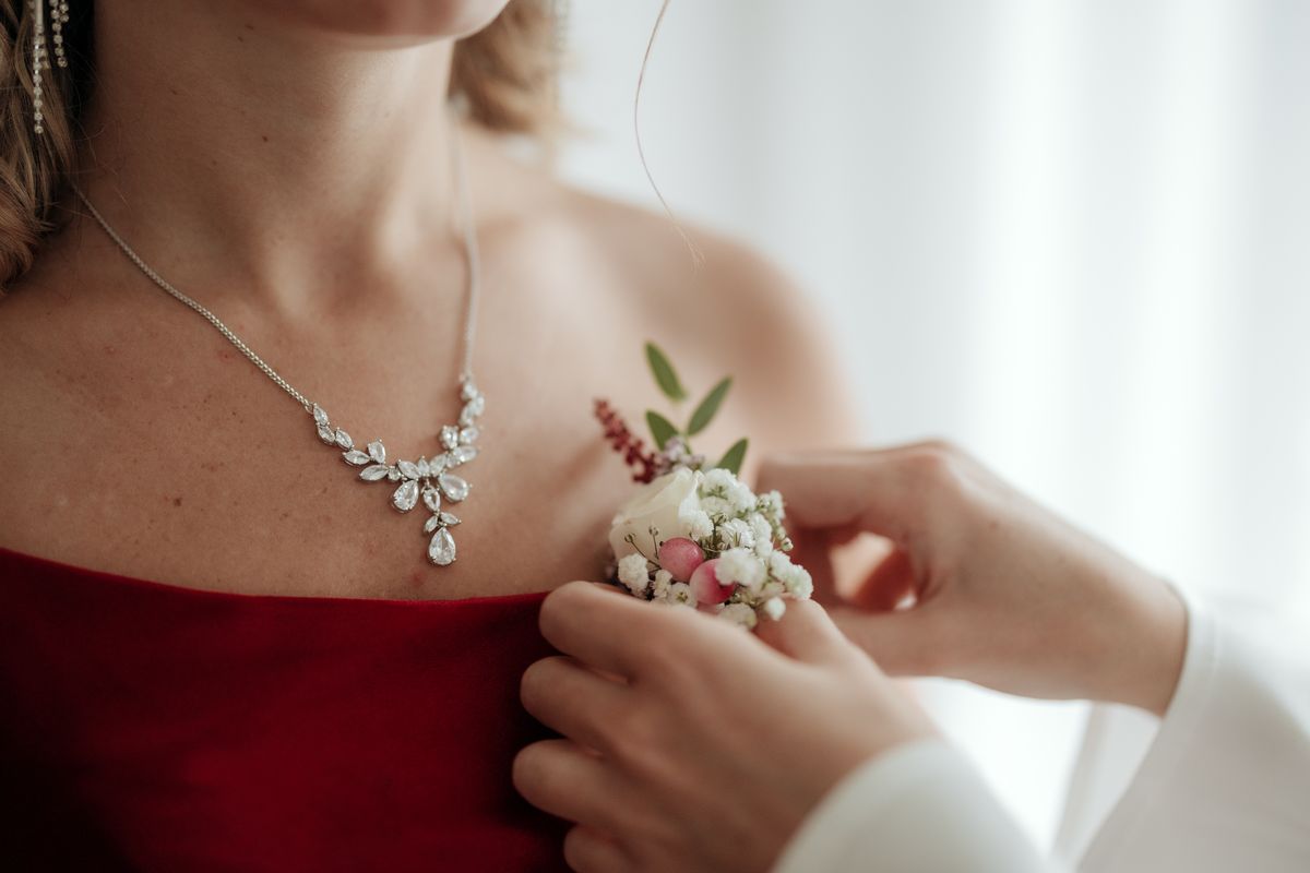 Floral pin being fastened to a red dress