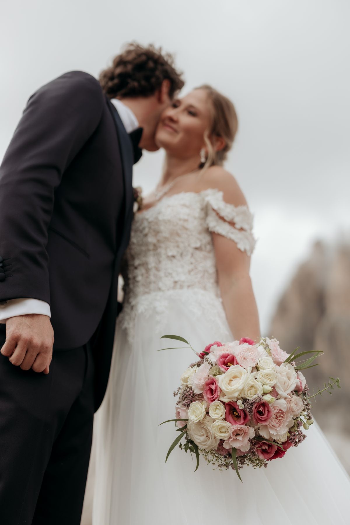 Couple kissing, the bride holding her bouquet
